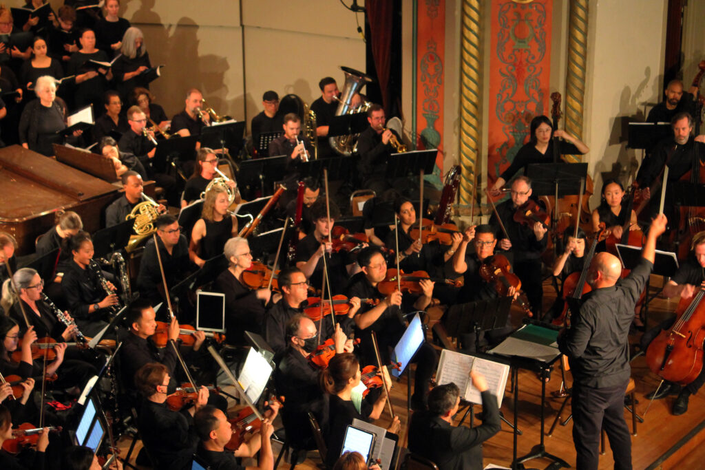 Dr. Brian Dehn conducts the orchestra and choir.