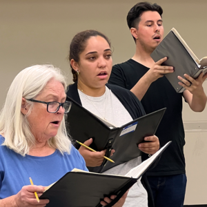 Two female singers and one male singer standing rehearsing Carmina Burana.