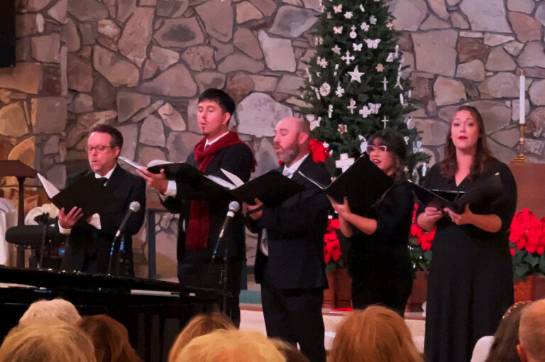 A quintet of singers performing next to a grand piano.
