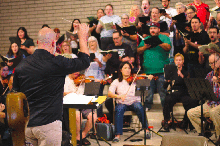 Dr. Brian Dehn standing in front of the choir and orchestra conducting.