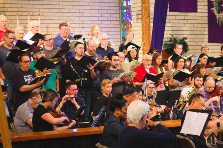 A group of singers standing and rehearsing.