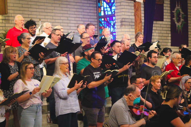 A group of singers holding music rehearses.