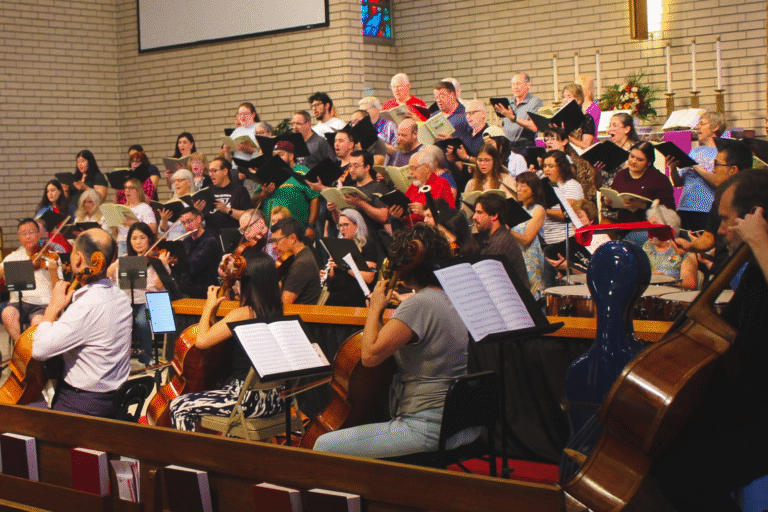A choir and orchestra rehearsing at the front of a church.