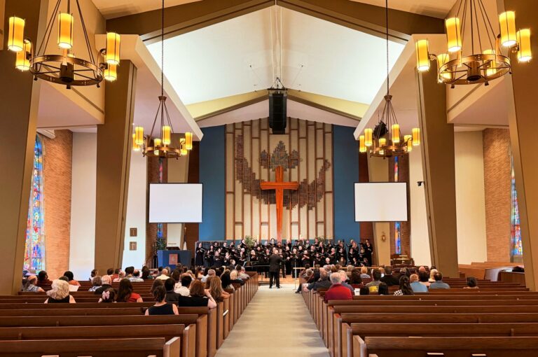 Audience in pews watch a choir dressed in all black perform.