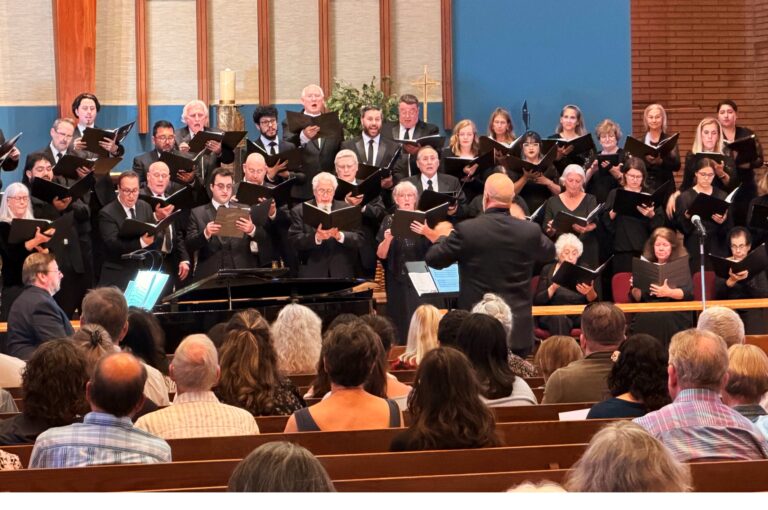 A conductor dressed in black conducts a choir.